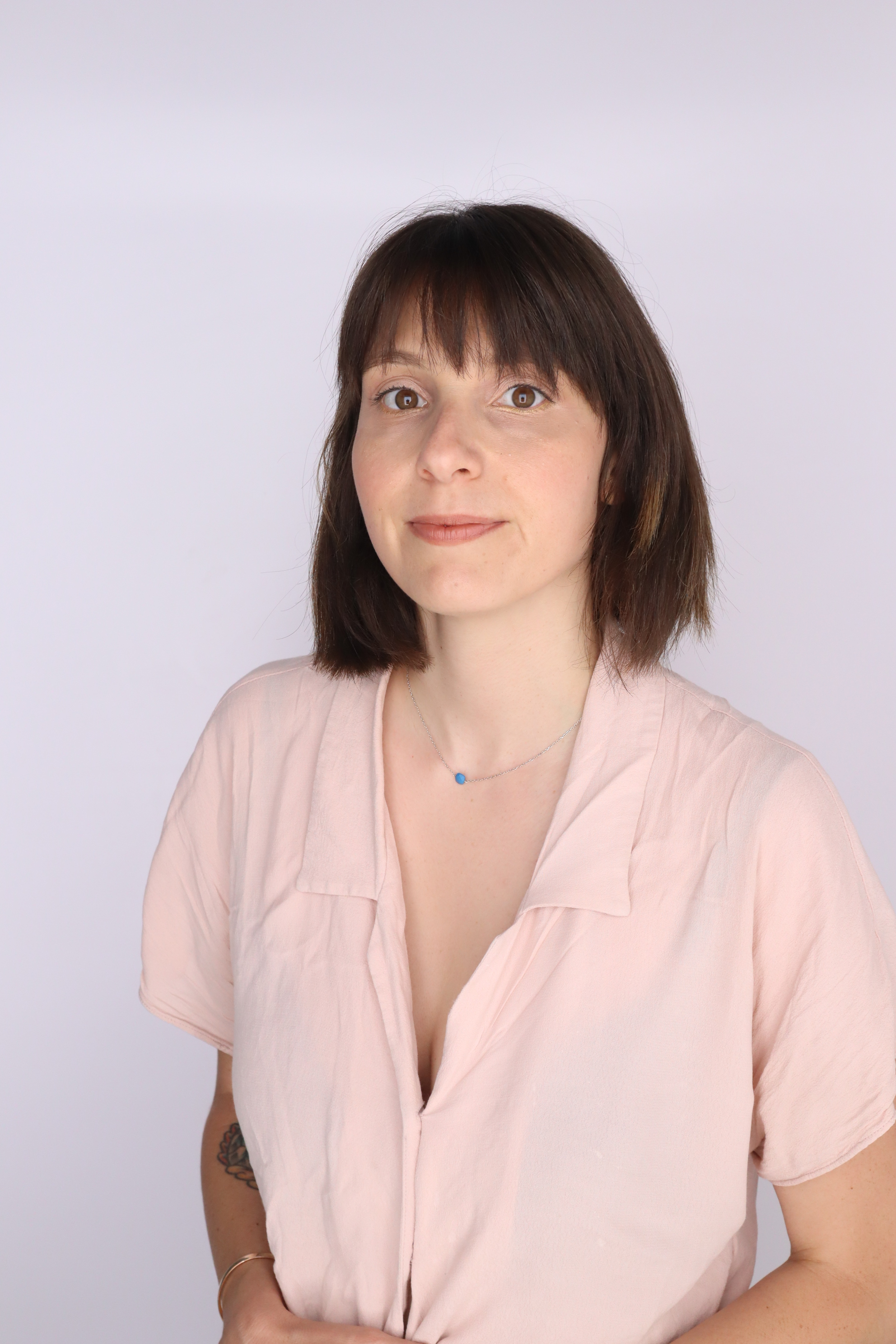 Portrait of Claire Cahen (white woman, medium length brown hair, brown eyes, pink blouse) posing for camera.